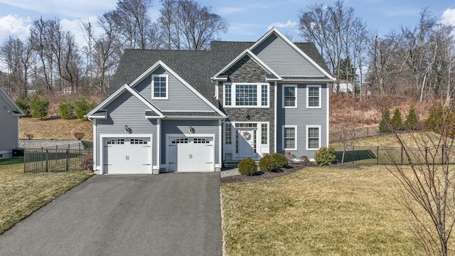 view of front of home featuring aphalt driveway, fence, a front lawn, and stone siding