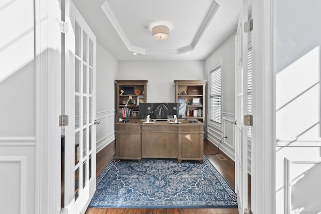 office area featuring dark wood finished floors, a tray ceiling, crown molding, and wainscoting