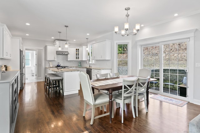 dining space with an inviting chandelier, recessed lighting, crown molding, and dark wood-type flooring