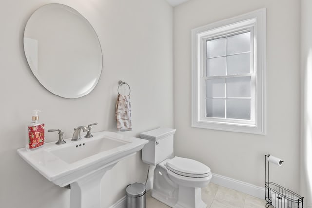 half bath featuring baseboards, toilet, and tile patterned flooring