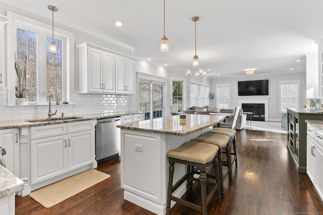 kitchen with a sink, decorative backsplash, white cabinets, dishwasher, and a center island