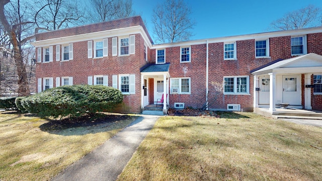 view of front of property with brick siding, a front lawn, and a chimney