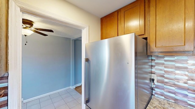 kitchen featuring light tile patterned flooring, freestanding refrigerator, a textured ceiling, baseboards, and ceiling fan