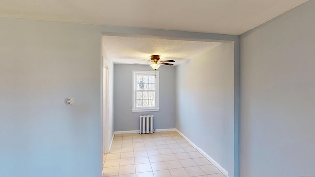 unfurnished room with light tile patterned floors, baseboards, a textured ceiling, ceiling fan, and radiator heating unit