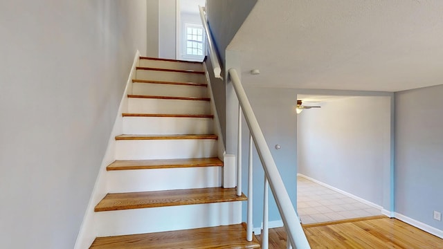 stairway with wood finished floors, baseboards, and ceiling fan