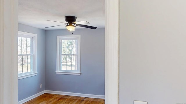 spare room with baseboards, wood finished floors, and ceiling fan