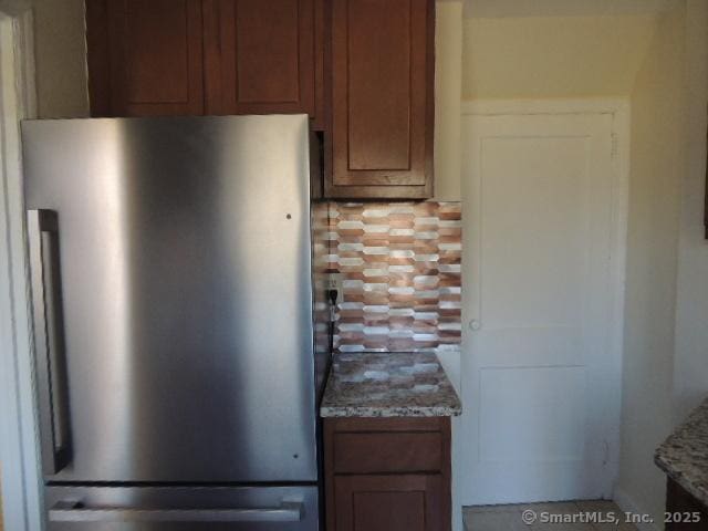 interior details with light stone countertops and freestanding refrigerator