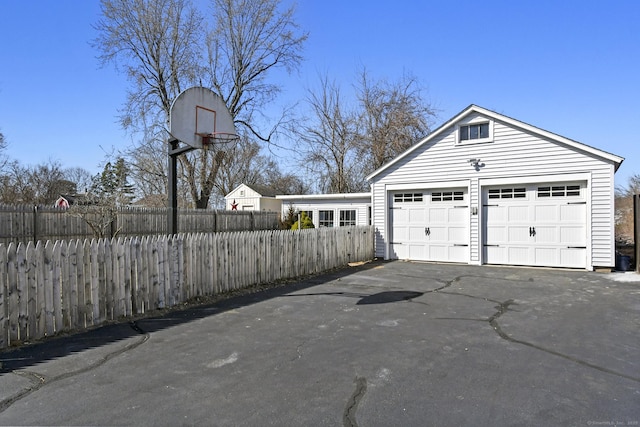 garage featuring aphalt driveway and fence