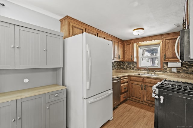 kitchen with brown cabinetry, backsplash, stainless steel appliances, and a sink