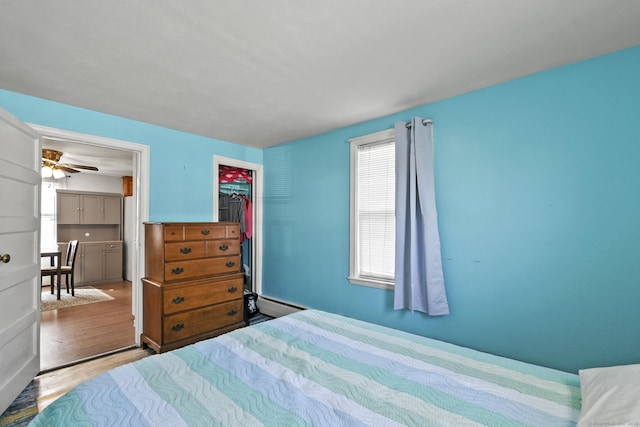 bedroom featuring a baseboard radiator, a closet, and wood finished floors