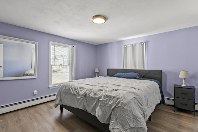 bedroom with wood finished floors and a baseboard radiator