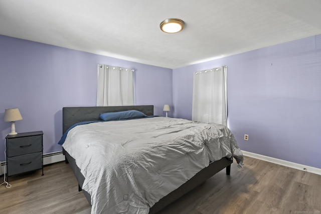 bedroom featuring a baseboard radiator, baseboards, and wood finished floors