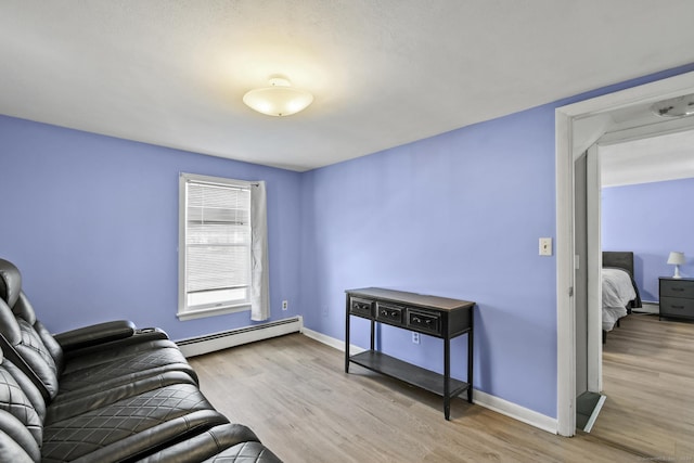 living room featuring light wood-style flooring, a baseboard heating unit, and baseboards