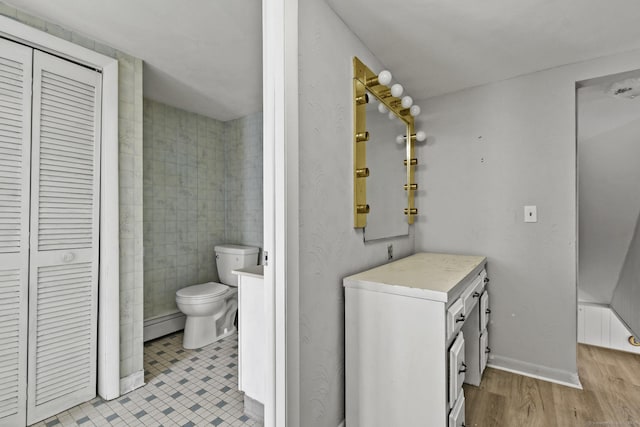 bathroom with a closet, toilet, vanity, and a baseboard radiator