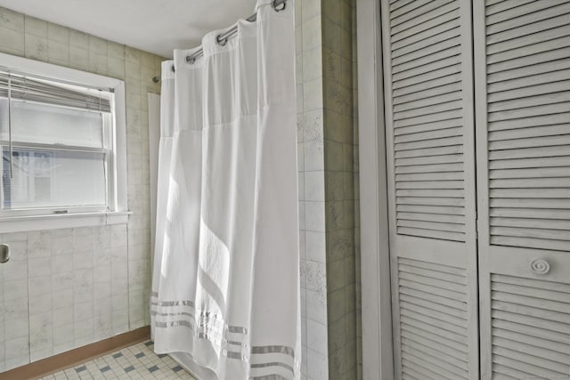 bathroom featuring tile patterned floors, tile walls, and a tile shower