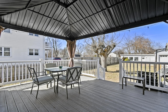 wooden deck featuring a lawn, an outdoor structure, outdoor dining area, and a fenced backyard