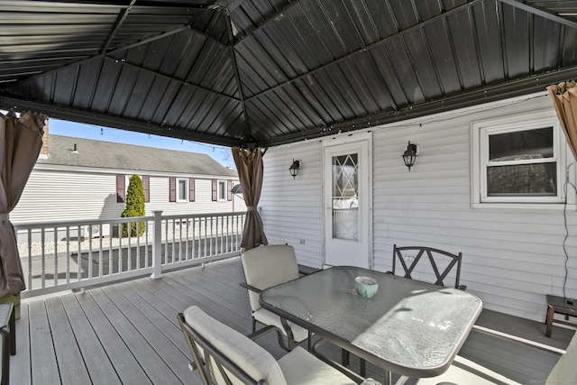 wooden terrace featuring a gazebo and outdoor dining space