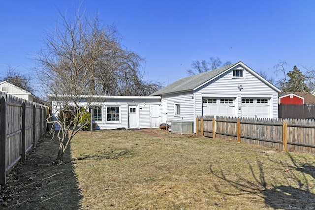 rear view of house featuring a garage, a yard, a fenced backyard, and an outdoor structure