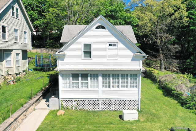 exterior space featuring a front yard, a trampoline, and a shingled roof