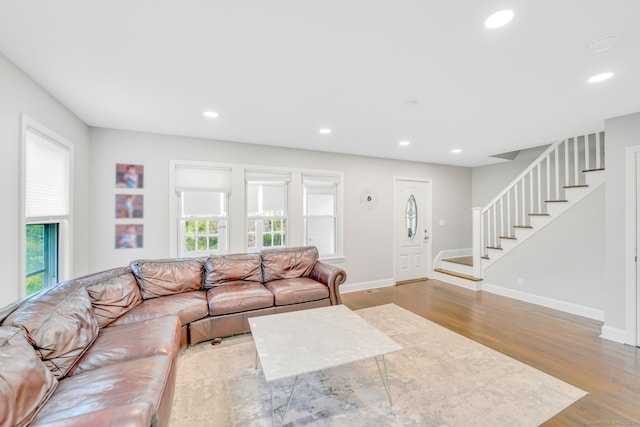 living room featuring recessed lighting, a healthy amount of sunlight, wood finished floors, and stairs