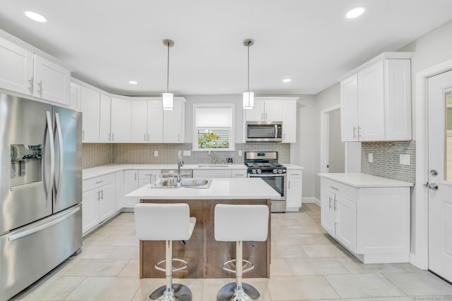 kitchen featuring a center island with sink, a sink, white cabinetry, stainless steel appliances, and light countertops