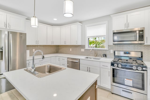 kitchen with backsplash, appliances with stainless steel finishes, light countertops, and a sink