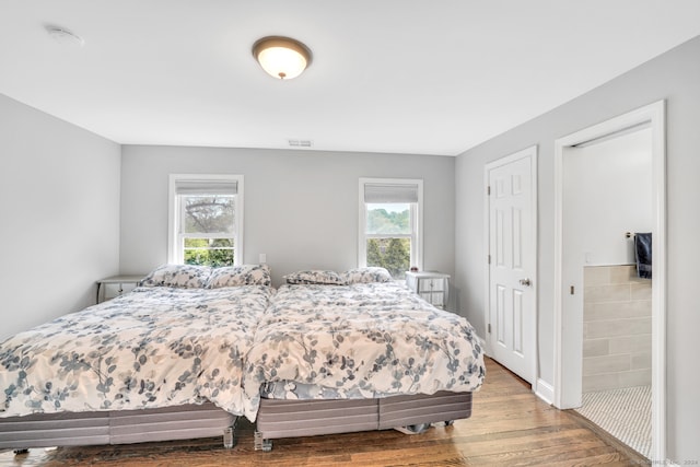 bedroom featuring visible vents, multiple windows, and wood finished floors