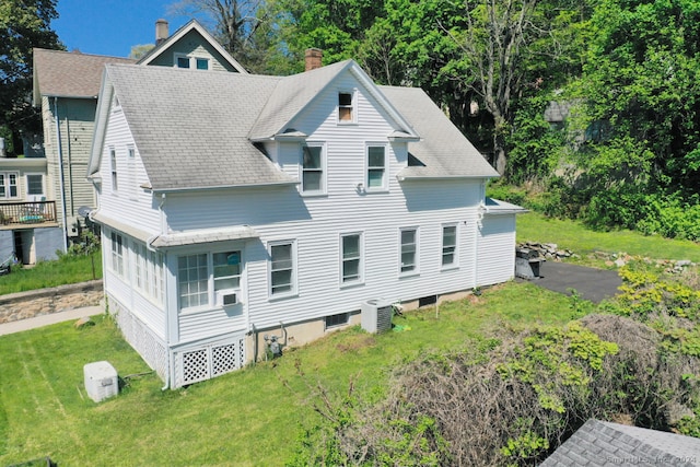 back of property with a lawn and roof with shingles