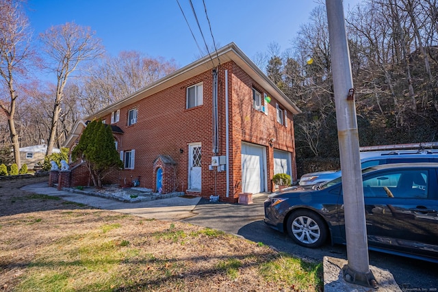 view of property exterior featuring brick siding, a garage, and driveway