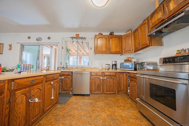 kitchen with under cabinet range hood, brown cabinetry, appliances with stainless steel finishes, and light countertops