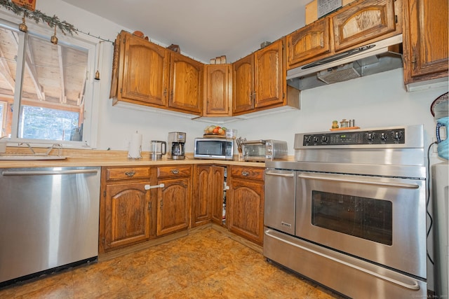 kitchen with brown cabinets, under cabinet range hood, a sink, stainless steel appliances, and light countertops