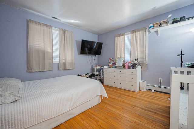 bedroom with visible vents, a baseboard radiator, and wood finished floors