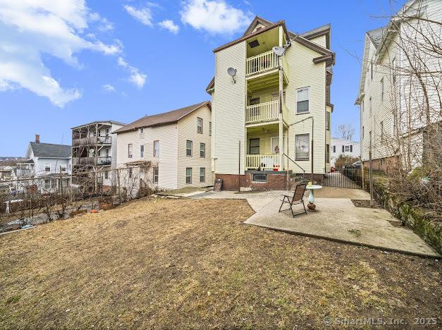 rear view of property featuring a patio area, a balcony, and fence