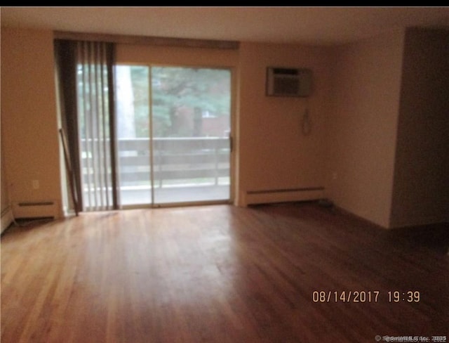 spare room featuring a baseboard radiator, an AC wall unit, and wood finished floors
