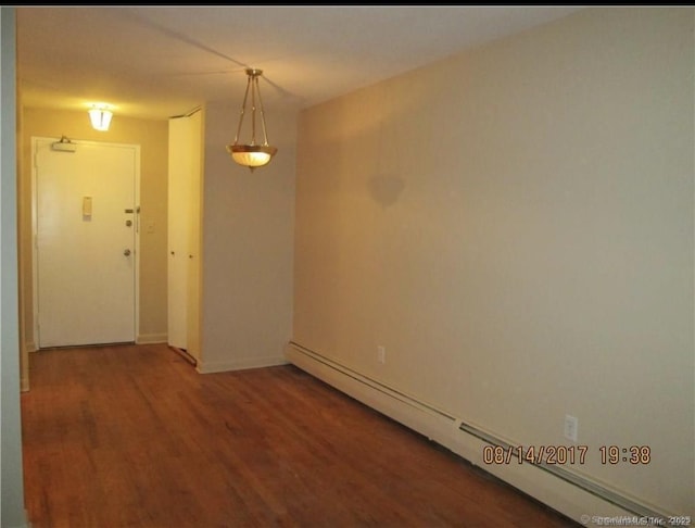 spare room with baseboards, a baseboard radiator, and wood finished floors