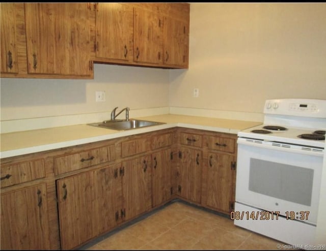 kitchen featuring a sink, light countertops, white electric range oven, and brown cabinets