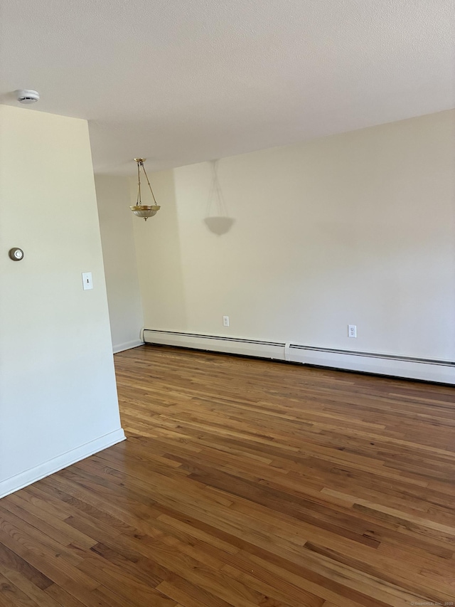 empty room with baseboards, a baseboard radiator, and wood finished floors