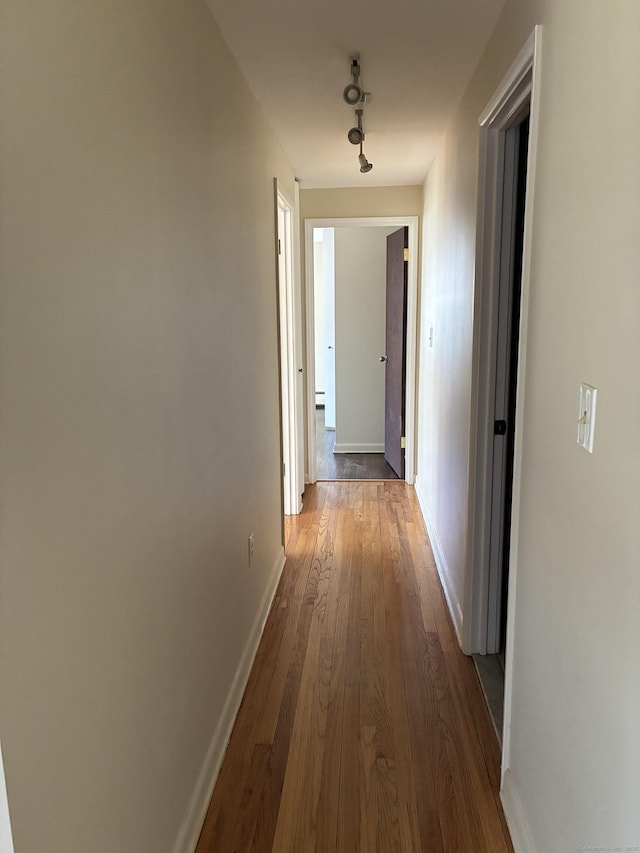 corridor with baseboards and hardwood / wood-style floors
