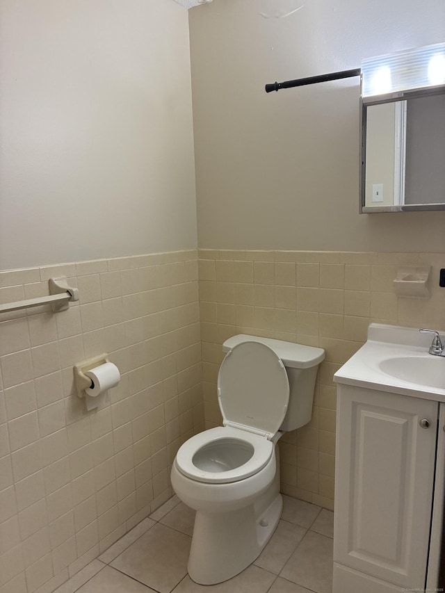 bathroom with tile walls, a wainscoted wall, toilet, and tile patterned floors