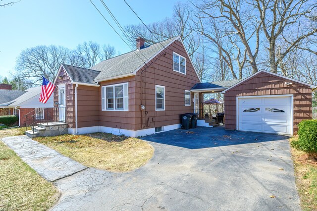 view of property exterior with a garage, driveway, roof with shingles, and a chimney