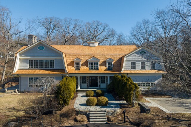 shingle-style home featuring a gambrel roof and a chimney