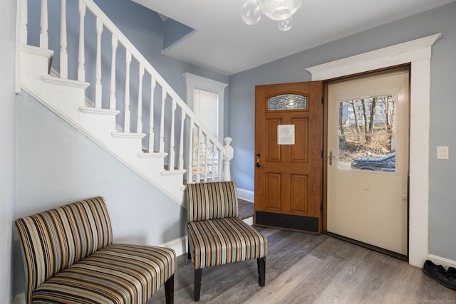 entryway featuring vaulted ceiling, stairway, wood finished floors, and a chandelier