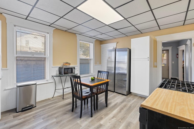 dining room with a paneled ceiling and light wood-style flooring