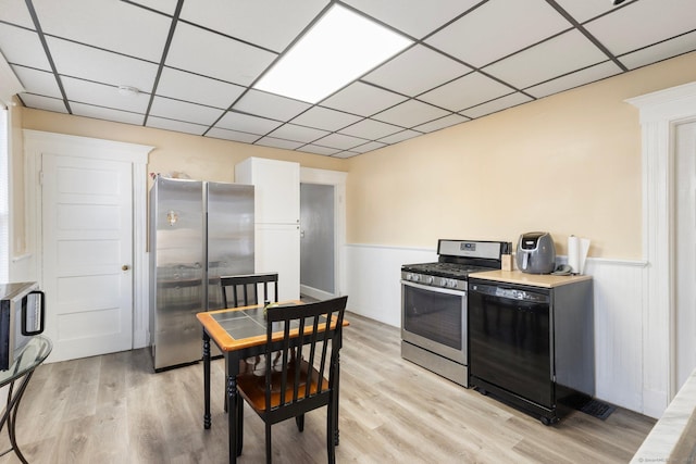 kitchen with a paneled ceiling, light wood-style floors, and appliances with stainless steel finishes