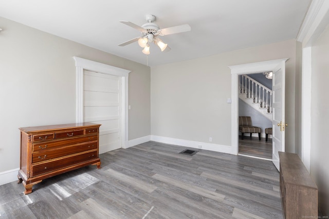unfurnished bedroom featuring ceiling fan, wood finished floors, visible vents, and baseboards