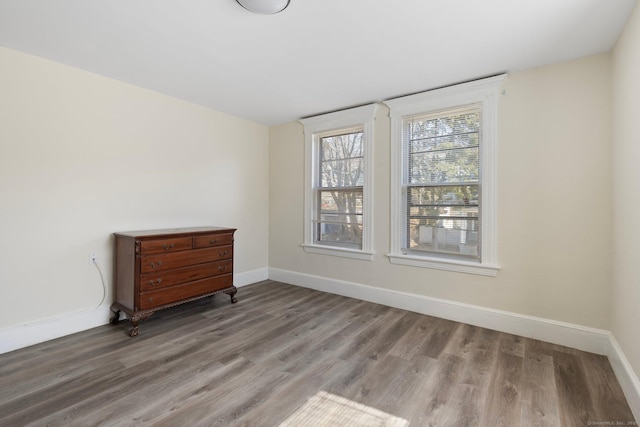 spare room featuring baseboards and wood finished floors