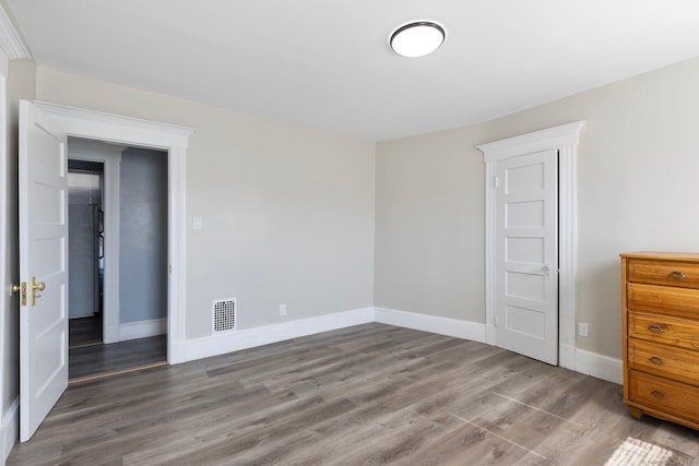 unfurnished bedroom featuring visible vents, baseboards, and wood finished floors