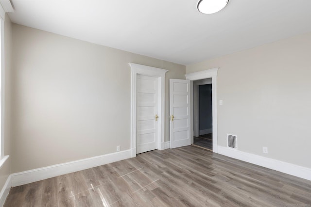 empty room featuring visible vents, baseboards, and wood finished floors