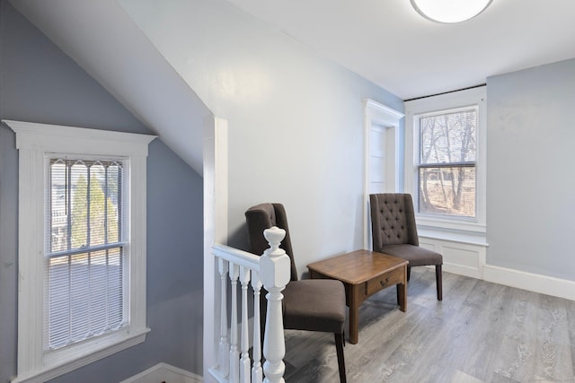 sitting room featuring vaulted ceiling, an upstairs landing, light wood-type flooring, and a healthy amount of sunlight