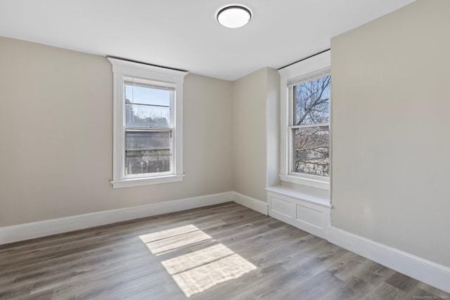 unfurnished room featuring a healthy amount of sunlight, baseboards, and wood finished floors